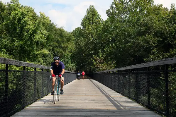 biker biking across bridge surrounded by trees in cordova, memphis, tennessee