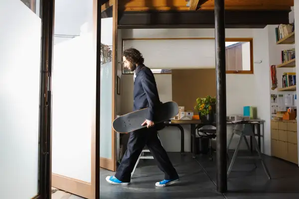 Businessman exiting office holding skateboard