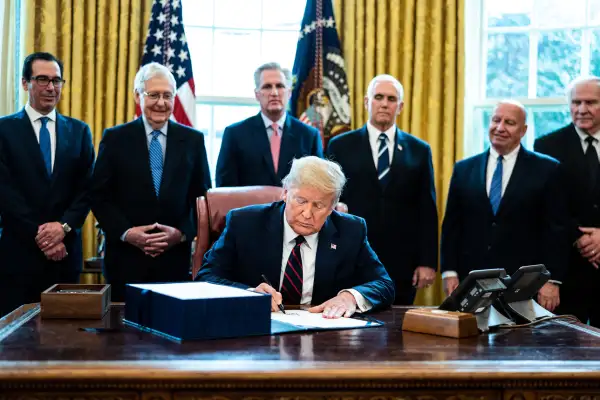 U.S. President Donald Trump signs the CARES Act in the Oval Office of the White House on March 27, 2020.