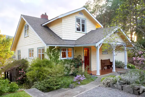 White house with grey roof surrounded by greenery