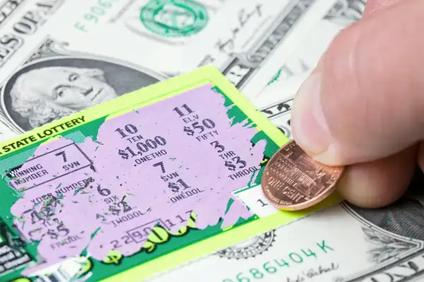 ottery player has scratched a winning ticket which rests on a dollar bill background.