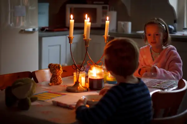 Young boy and girl sitting at the table eating breakfast by candle light.