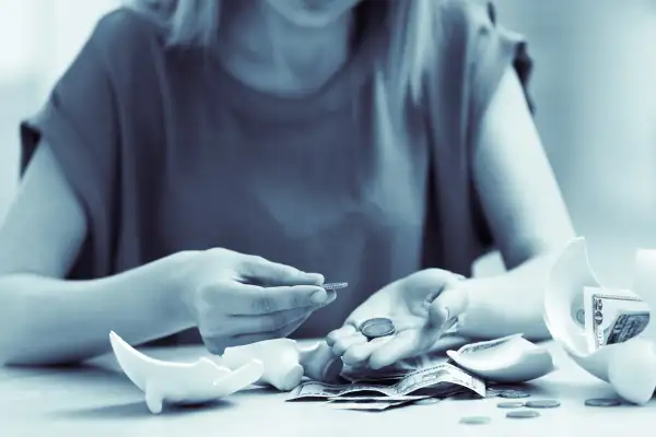 Woman counting money from her broken piggy bank