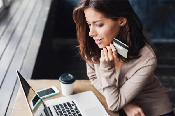 woman staring into her computer holding a credit card