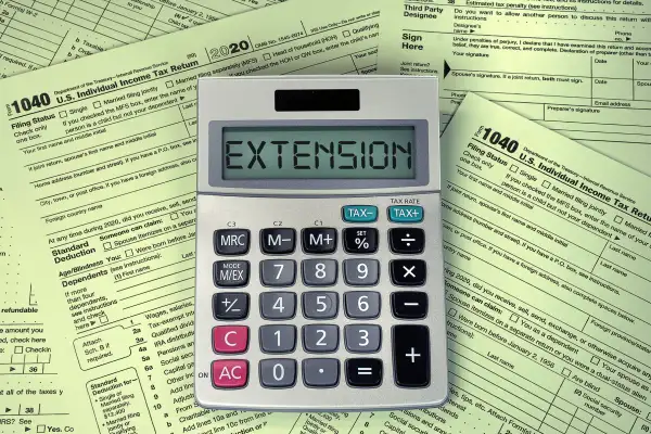 Calculator with the word extension on top of multiple 1040 tax forms