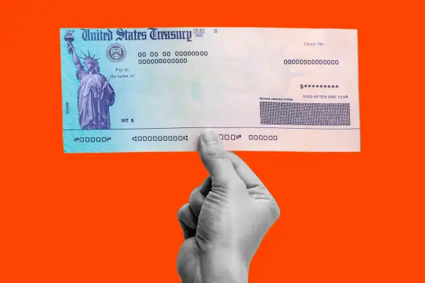 Photograph of a hand holding a United States Treasury Check on a colored background