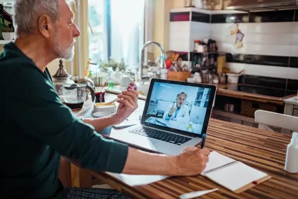 Close up of a senior man consulting with his doctor online on his laptop