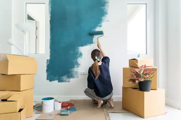 Young woman painting interior wall with a paint roller