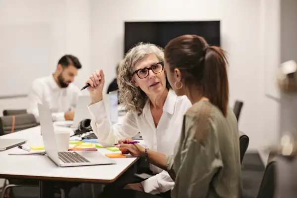 Older businesswomen discussing work over laptop with co-worker
