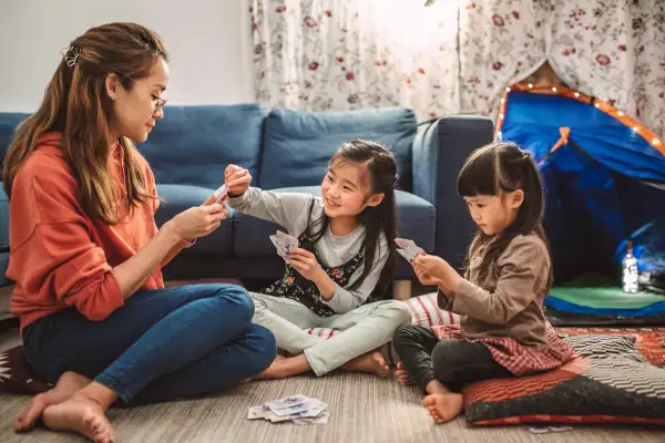 Woman playing cards in her living room with her two daughters