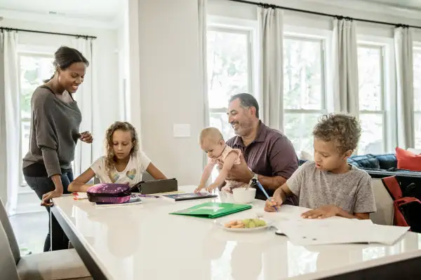 Mother and father helping their kids with their homework in the kitchen