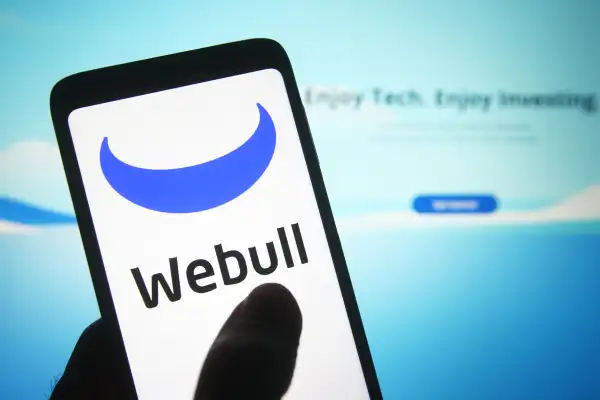 Smartphone displaying the Webull logo with the company's website in the background