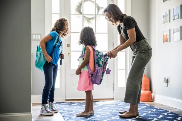 Mother packing daughters backpacks for school