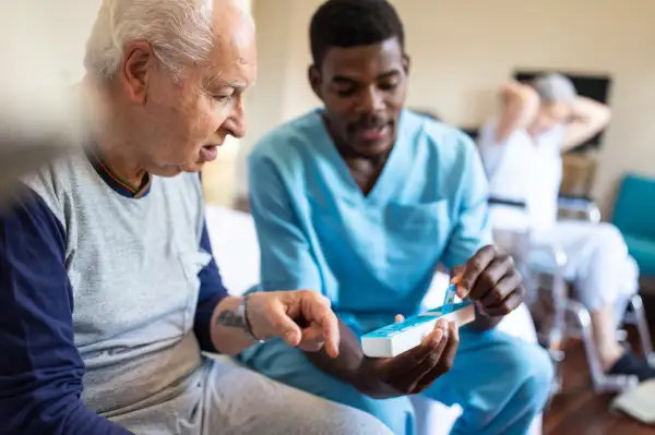 Male nurse giving instructions to senior patient when to take his pills in nursing home