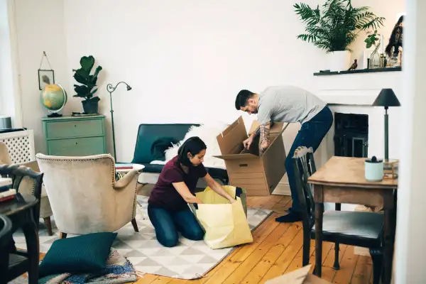 Couple unpacking boxes together in living room at new home