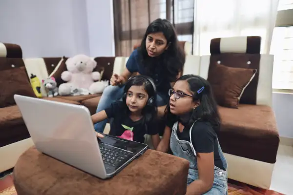 Sisters using a laptop with their mother’s assistance