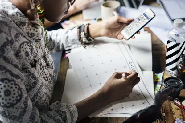 A woman is writing a note on a calendar.