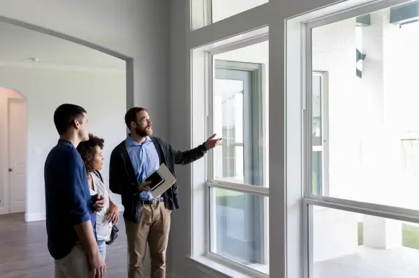 Real estate agent gestures toward a beautiful view out the window of a new home to a potential buyer