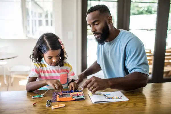 Father and daughter working on science project at home