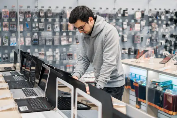 Young male choosing a laptop at electronic store