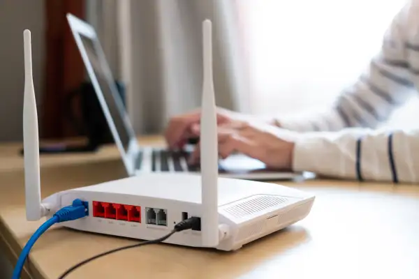 Internet router on a desk with a person working on their computer in the background