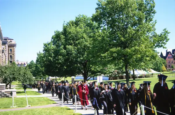 Line of graduates wearing caps and gowns on a university campus