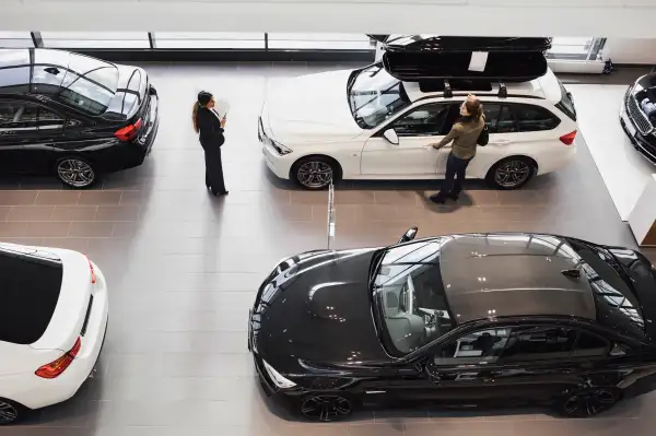 High angle view of saleswoman and customer looking at car in showroom