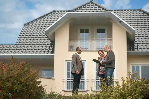 Real estate agent with potential buyers in front of residential house