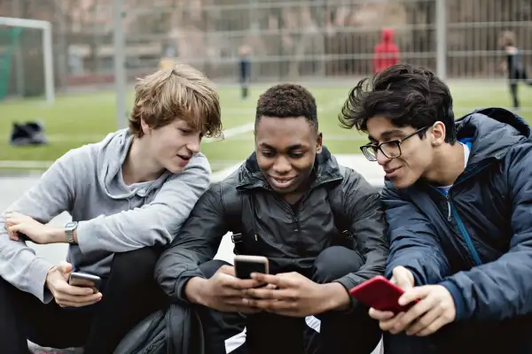 Three teenage boys looking at their smartphones