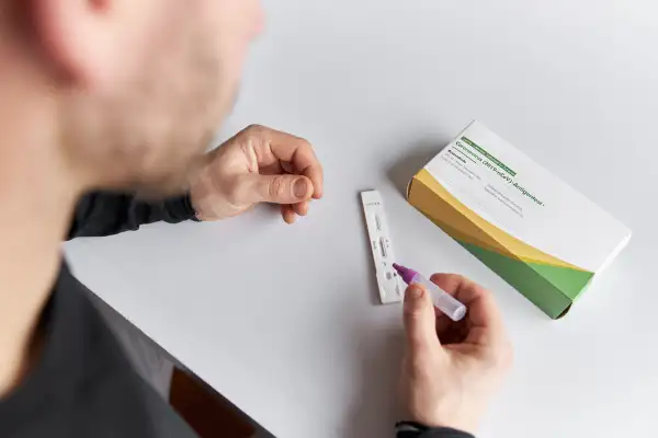 A close up of a man's hands doing a rapid corona test or antigen test