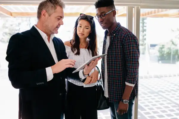 Realtor shows data on tablet to a interracial couple during a home appraisal