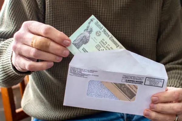 Closeup of a person taking a stimulus check out from an envelope