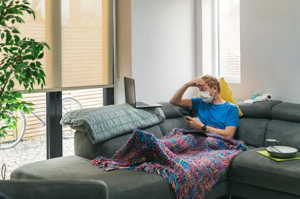Man sick with Covid-19 isolated and wearing a face mask in his living room