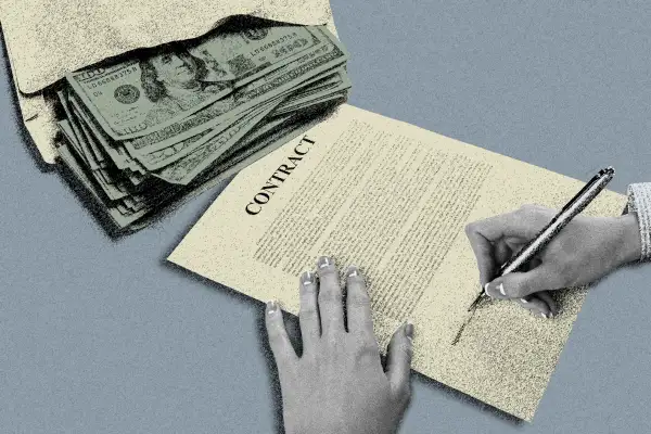 Close-up of hands signing a job contract and an envelope with money on the side