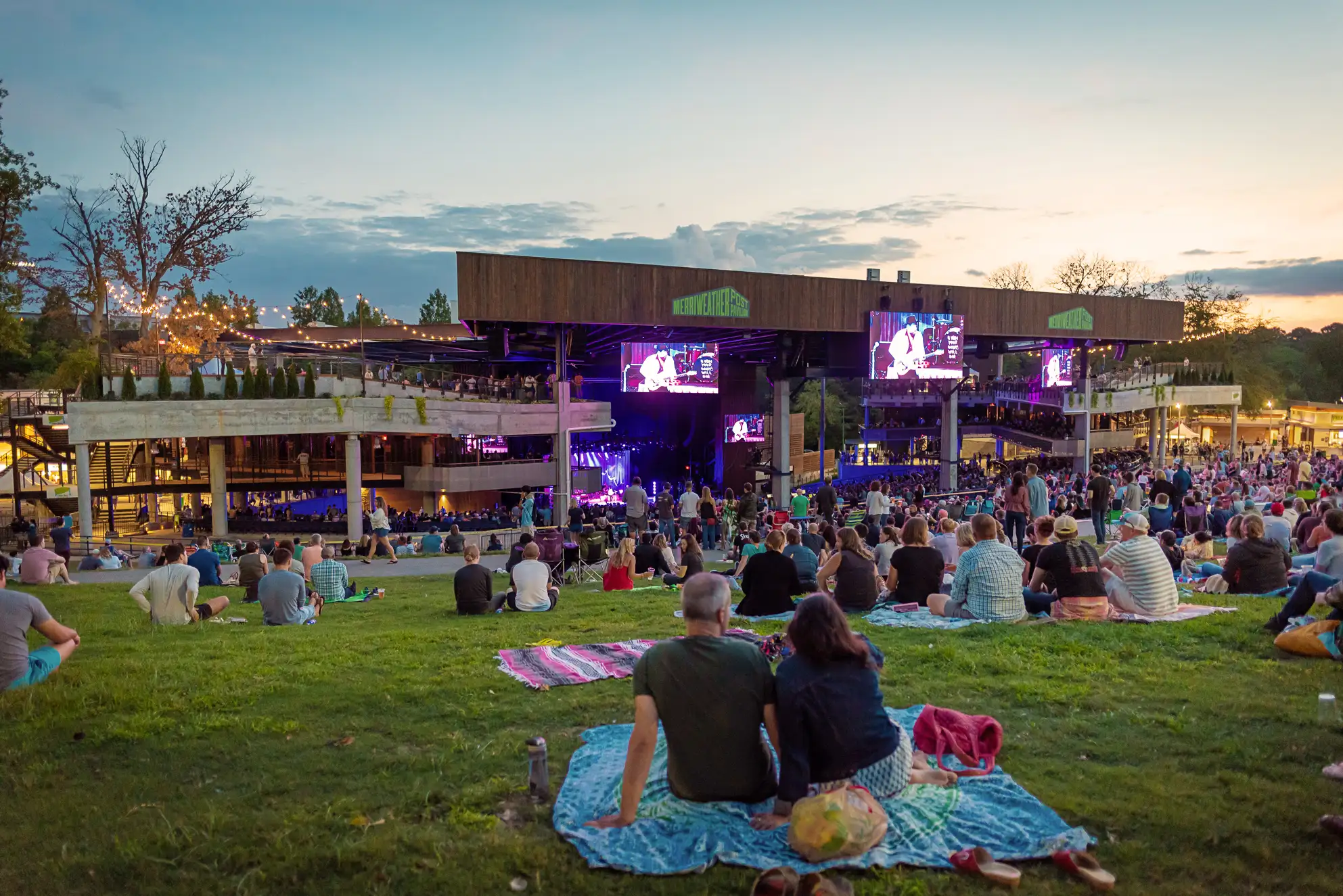 People lay on blankets in the lawn while listening to live music at the The Merriweather Post Pavilion in Columbia, Maryland