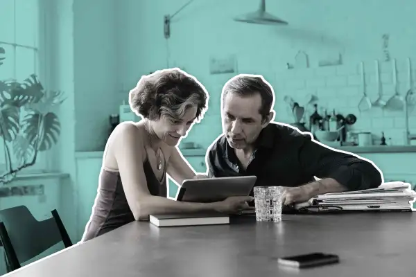 Couple At Kitchen Table Looking At Tablet Computer