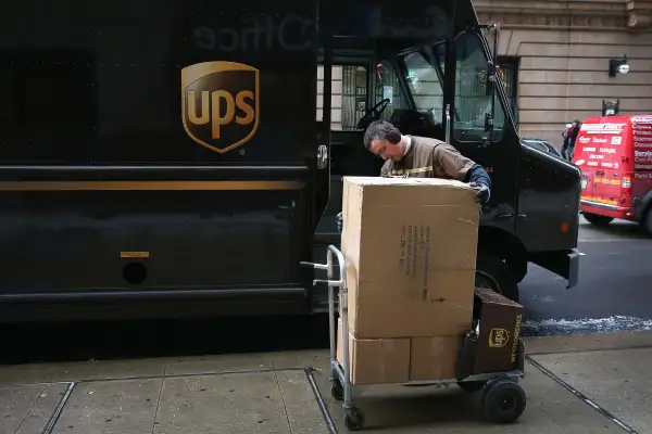 UPS Delivery Worker Mounting Boxes On Cart