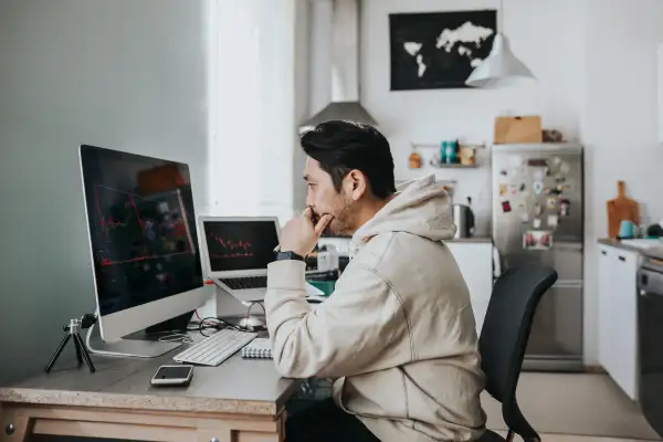 Man studying stock market charts on his personal computer at home