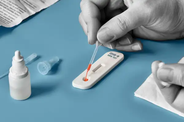 Close-up of a hand applying a sample onto a rapid detection Covid-19 Test