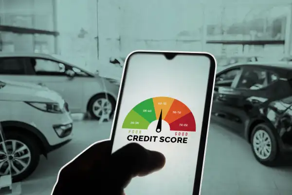 Hand Holding A SmartPhone Inside A Car Dealership With Credit Score On Screen