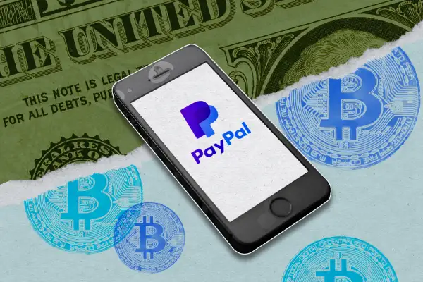 Photo illustration of a phone with the PayPal app and a dollar being converted to crypto