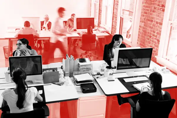 Photo of a busy office with multiple employees working from their desks