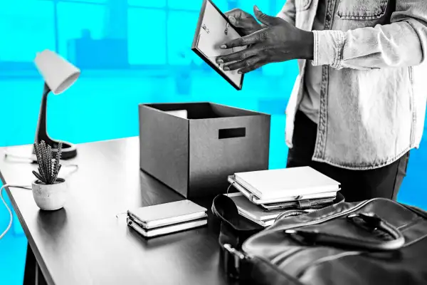 Person In Office Placing Desk Items In Box