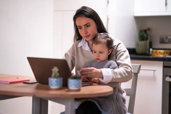 Young mother using the computer while kid sits on her lap
