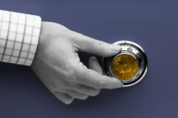 Hand turning a safe lock with a crypto coin emblazoned on the dial.