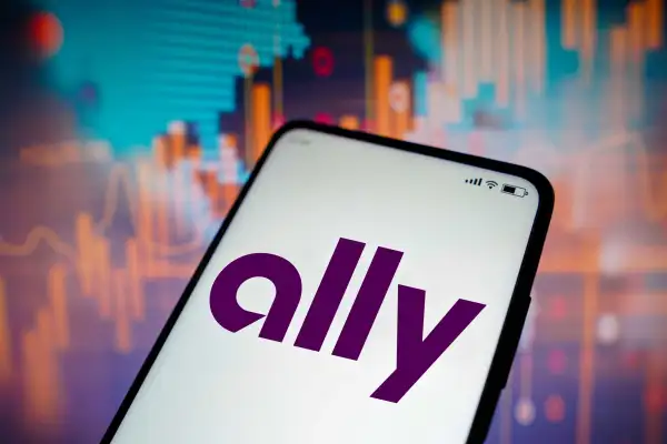 Ally Logo On Smartphone Screen In Front Of Stock Market Graphics