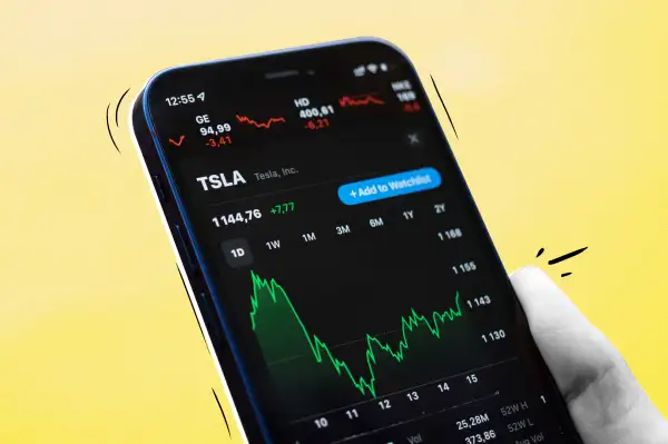 Close-up of a hand holding a smartphone looking at Tesla Stock