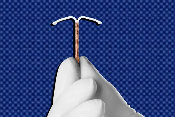 Close up of a gloved hand holding an IUD device