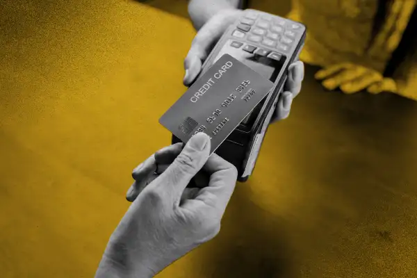 Close up of a hand presenting a credit card on a point of purchase machine
