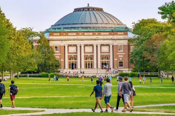 Students walk outdoors on lawn of University campus